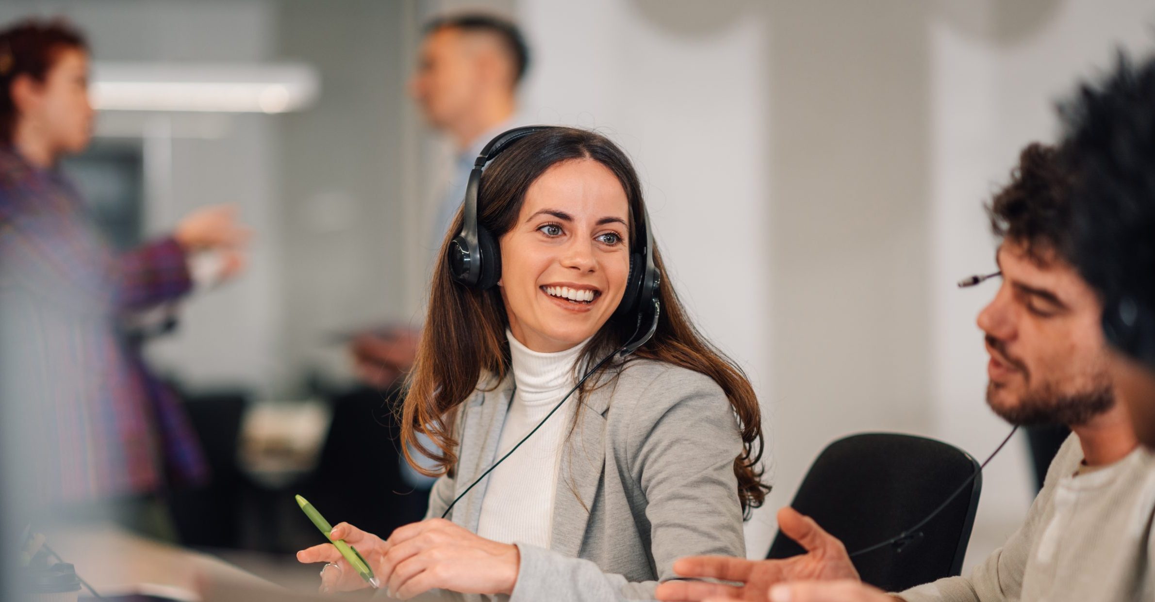 A servicdesk worker is sitting at call center in corporate company and having a phone call on headsets.